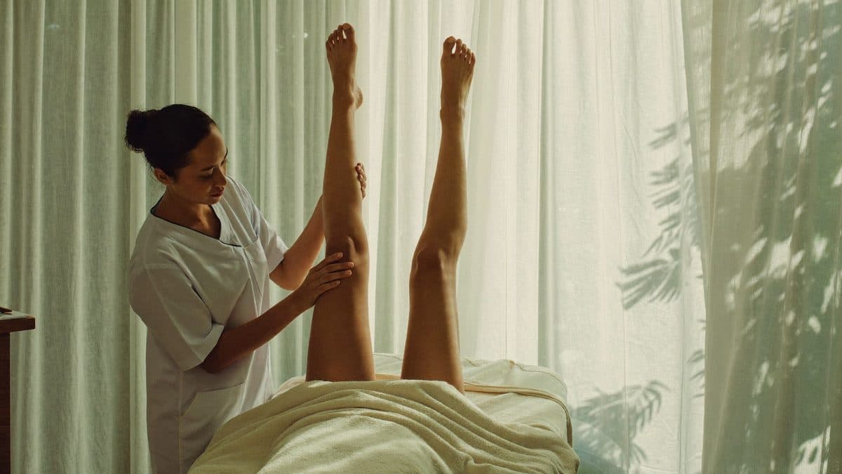 Soin de drainage lymphatique des jambes, gestes manuels doux dans une lumière chaleureuse