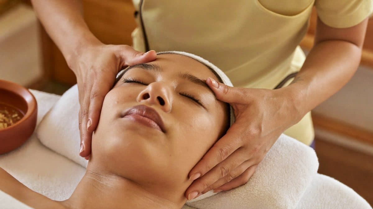 Massage Kobido du visage en cabinet, mains de la praticienne sur le visage détendu d’une cliente